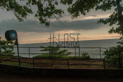 a sign that reads last wishes in front of the ocean at The Lost Hostel, Varkala - Helipad in Varkala