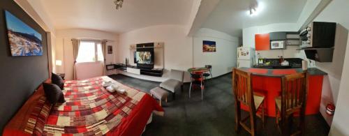 Il comprend un salon avec un lit rouge et une cuisine. dans l'établissement PlaceresCC, à Ushuaia