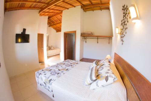 a bedroom with a white bed with a wooden ceiling at Pousada Morro Verde in Águas de Lindoia