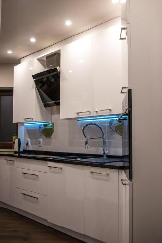 a kitchen with white cabinets and a sink at Apartamenty Pod Łysicą & SPA - przy stoku, basen, jacuzzi, sauna in Krajno Pierwsze