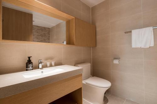 a bathroom with a toilet and a sink and a mirror at Chestertons Sokcho in Sokcho