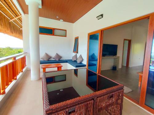 Bohol Coastal View Hotel في Taiwala: غرفة مع شرفة مع أريكة وتلفزيون
