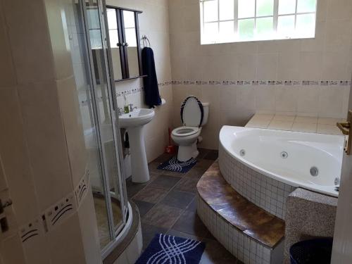 ein Badezimmer mit einer Badewanne, einem WC und einem Waschbecken in der Unterkunft QUARTERDECK VILLA in Deneysville