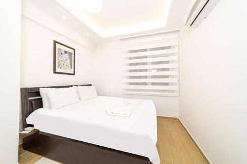 białe łóżko w białym pokoju z oknem w obiekcie Cozy w mieście Antalya