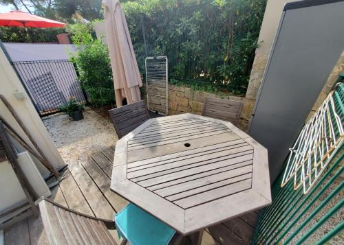 einen Holztisch und Stühle auf einer Terrasse mit einem Sonnenschirm in der Unterkunft Appartement avec piscine proche bord de mer in Cagnes-sur-Mer