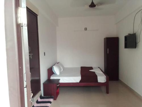 Dormitorio pequeño con cama y TV en Emirates Residency, en Pudunagaram