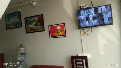 TV de pantalla plana colgada en una pared con fotografías en Emirates Residency, en Pudunagaram