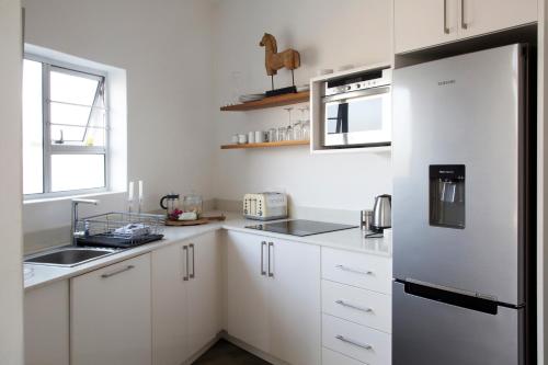 a kitchen with white cabinets and a stainless steel refrigerator at Sunshowers Plett in Plettenberg Bay