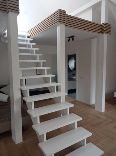 a staircase in a living room with white steps at Apartamenty Osmolice w Stawach in Dęblin
