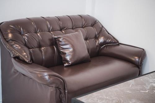 a brown leather couch with a pillow on a table at VEVILLA in Bangkok