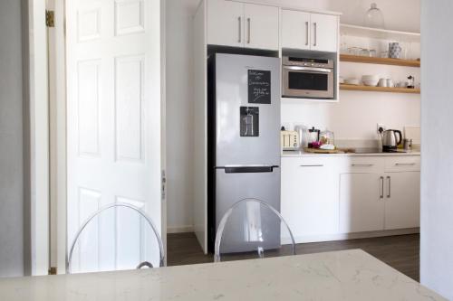 a kitchen with white cabinets and a refrigerator at Sunshowers Plett in Plettenberg Bay