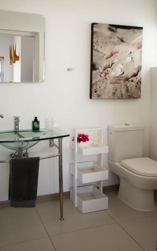 a bathroom with a toilet and a glass table at Sunshowers Plett in Plettenberg Bay