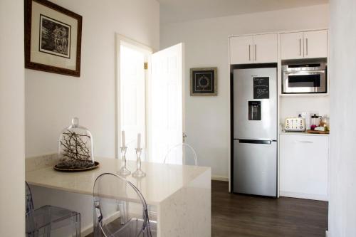 a kitchen with a refrigerator and a counter with chairs at Sunshowers Plett in Plettenberg Bay