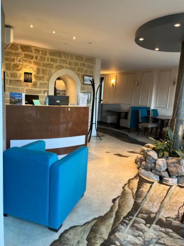 un hall d'entrée avec un canapé bleu et un bar dans l'établissement Hôtel La Vinaigrerie LOGIS, à Joinville
