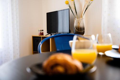 una mesa con un plato de comida y un vaso de zumo de naranja en L'Amarillo Clim Wifi Centre ville 4 pers, en Lézignan-Corbières