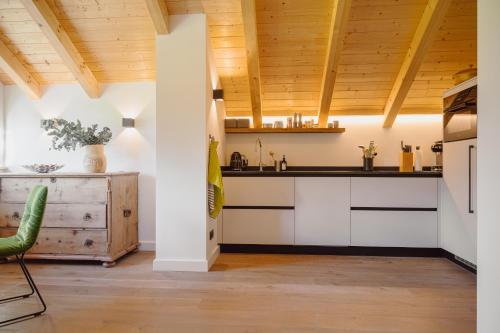 a kitchen with white cabinets and a wooden ceiling at DAS SALZBERG Hideaway Bad Aussee - Adults only in Bad Aussee