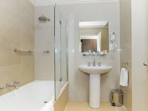 uma casa de banho branca com um lavatório e um chuveiro em Harbourside Views 503 Sebel Kiama em Kiama