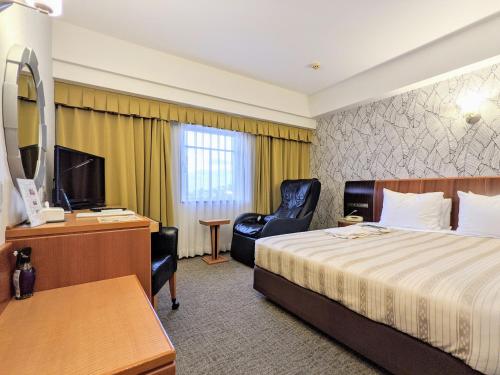 a hotel room with a bed and a desk and a chair at GRG Hotel Naha Higashimachi in Naha