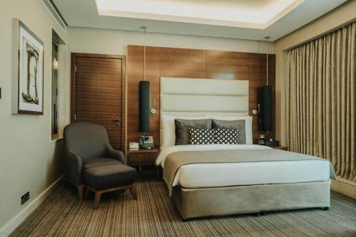 a hotel room with a bed and a chair at Grand Millennium Sulaimani in As Sulaymānīyah