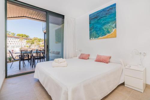 a white bedroom with a bed and a balcony at Mirador Blue G in Cala de Sant Vicenc
