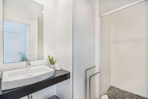 a white bathroom with a sink and a shower at Mirador Blue G in Cala de Sant Vicenc