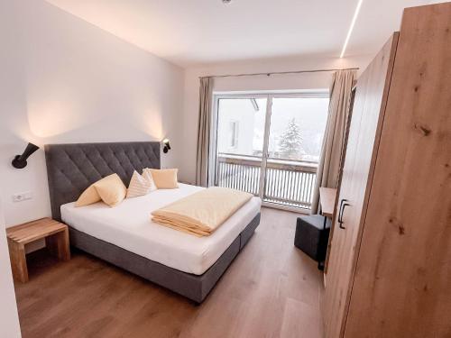 ein Schlafzimmer mit einem großen Bett und einem großen Fenster in der Unterkunft Glüxplatzl GmbH Appartements am Wald in Sankt Martin am Tennengebirge