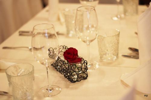 a table with wine glasses and a red rose in a box at Rooms & Restaurant Ostarija in Dolenjske Toplice