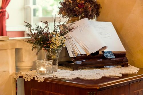 a table with a bunch of books and a vase of flowers at Rooms & Restaurant Ostarija in Dolenjske Toplice