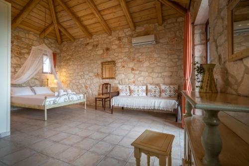 a room with two beds and a stone wall at Myrties stone houses - Ta Petrina in Vasilikos