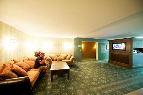 a woman sitting on a couch in a hotel room at Villa Hotel Theresa in Rakvere