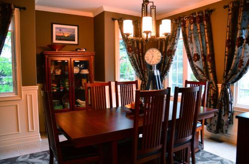 a dining room table with chairs and a clock on the wall at Explorer House Bed & Breakfast in Niagara on the Lake