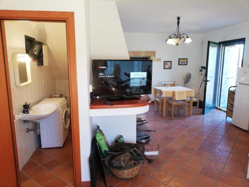 ein Wohnzimmer mit einem TV und eine Küche mit einem Tisch in der Unterkunft Villa Tirso in Sorso