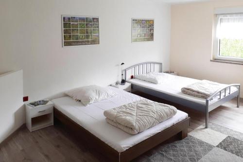 2 łóżka w pokoju z białymi ścianami w obiekcie Terraced house, Kaltennordheim w mieście Fischbach