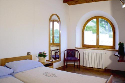 1 dormitorio con 1 cama, 1 silla y 2 ventanas en Apartment in Residence La Ginestra in Montelparo, en Montelparo
