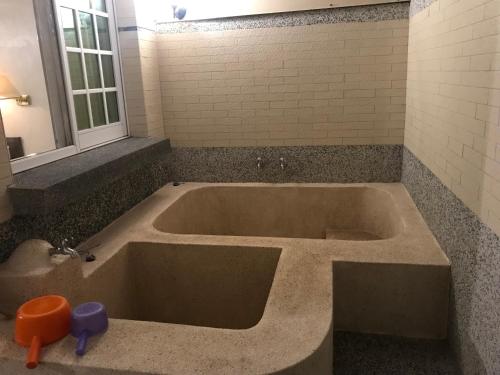a large bath tub in a bathroom with a window at Songboling Hot Spring Inn in Liugui