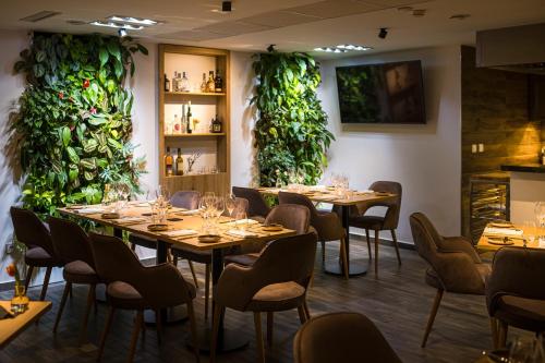 a restaurant with tables and chairs with plants on the walls at Kistücsök Food & Room in Balatonszemes