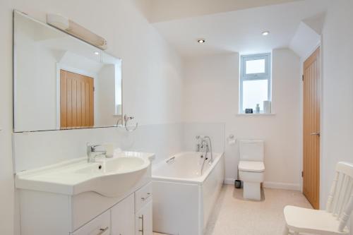 a white bathroom with two sinks and a toilet at A Spacious Seaside house in Hampton, Herne Bay in Herne Bay