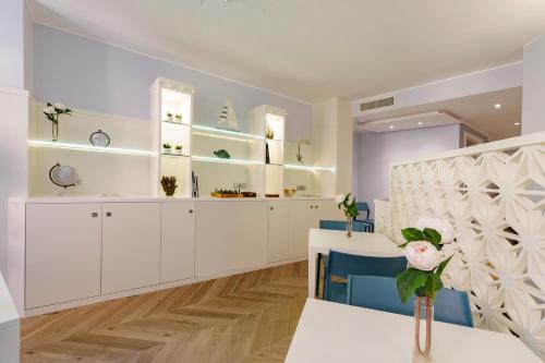 a dining room with white cabinets and blue chairs at Hotel Baylle in Cagliari