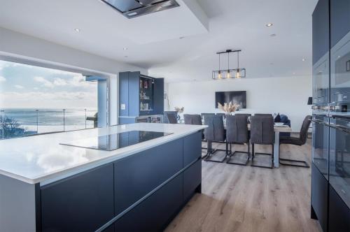 a kitchen with blue cabinets and a view of the ocean at Sunrise - 5 Bedroom Luxurious Holiday Home - Pendine in Pendine