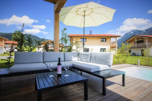 a couch and a table with wine glasses on a patio at Bergchalet Falkenstein, Inzell in Inzell
