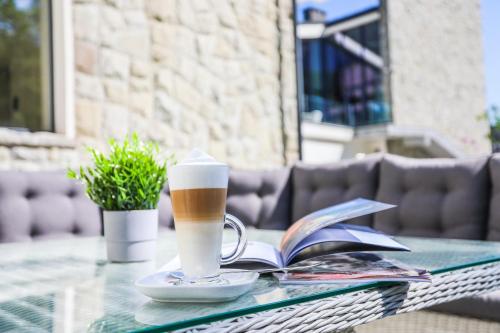 a glass table with a cup of coffee and a book at Magnus Resort in Szczyrk