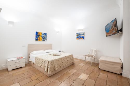 a white bedroom with a bed and a chair at Casa Malu in Positano