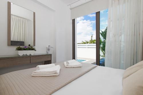 een witte slaapkamer met een bed met handdoeken erop bij Villa Serena in Protaras