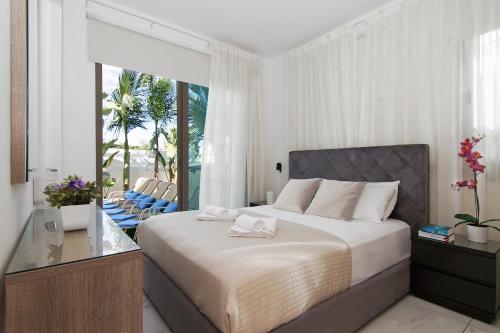 een slaapkamer met een bed en een balkon met stoelen bij Villa Serena in Protaras