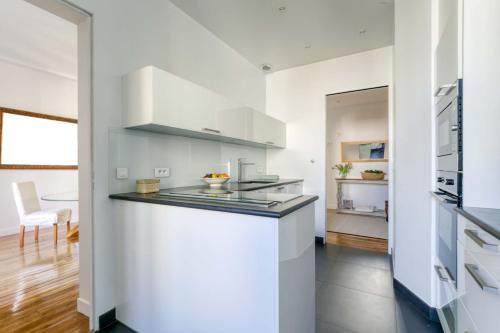 - une cuisine avec des murs blancs et un comptoir dans l'établissement Superbe appart de 129m2, 3 ch-Neuilly 2 min Paris, à Neuilly-sur-Seine