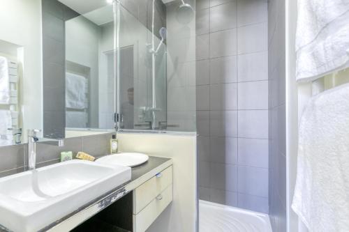 une salle de bain blanche avec un lavabo et un miroir dans l'établissement Superbe appart de 129m2, 3 ch-Neuilly 2 min Paris, à Neuilly-sur-Seine