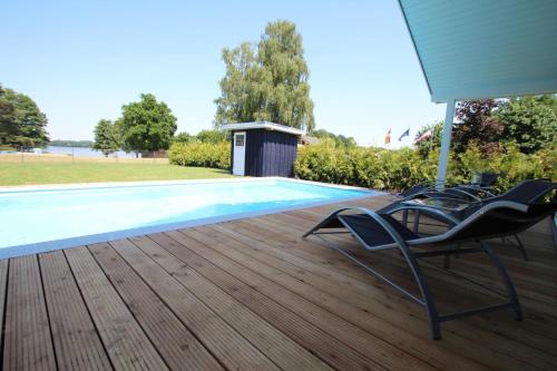 a pair of chairs sitting on a deck next to a swimming pool at Ferienhaus mit Pool und Sauna am Duemmer See in Dümmer