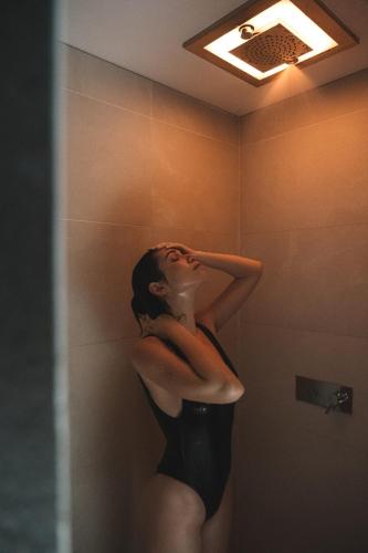 a woman standing in a shower in a bathroom at Elite Hotel & Spa in Mestre