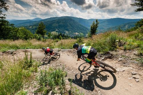 two people riding bikes on a dirt road at Magnus Resort in Szczyrk