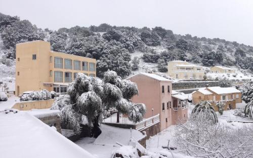a city covered in snow with buildings and a tree at Hotel Alata in Alata